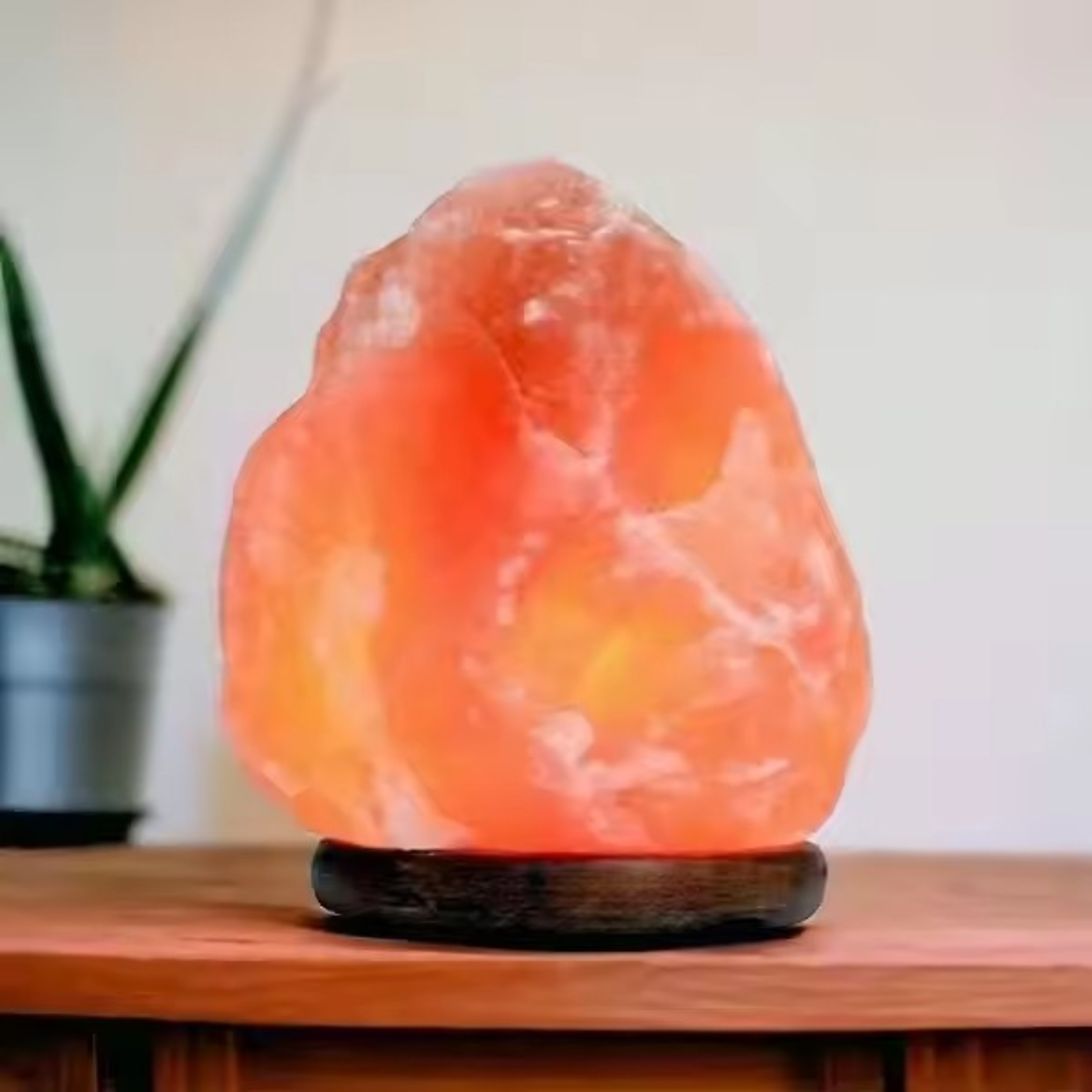 Natural rough Himalayan salt lamp glowing warm on a wooden base