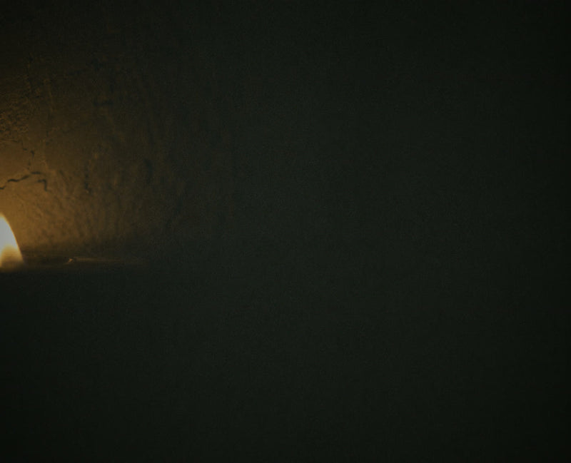 A candle flame at the edge of a dark frame