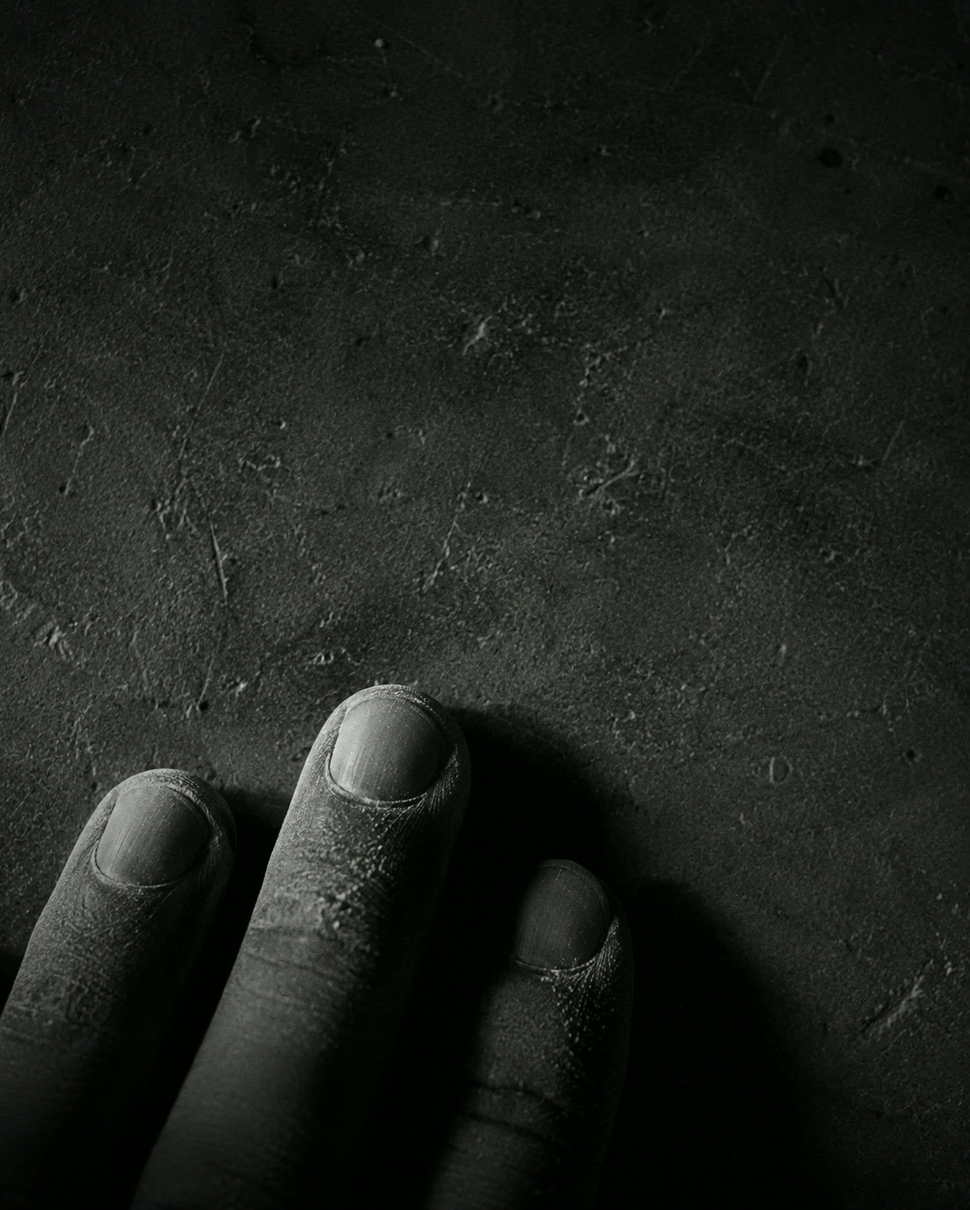 Fingertips resting on a dusty stone surface