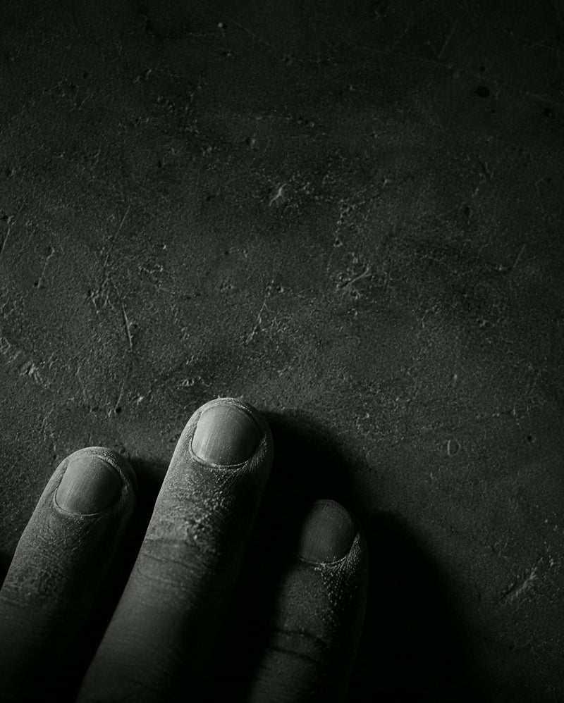 Fingertips resting on a dusty stone surface