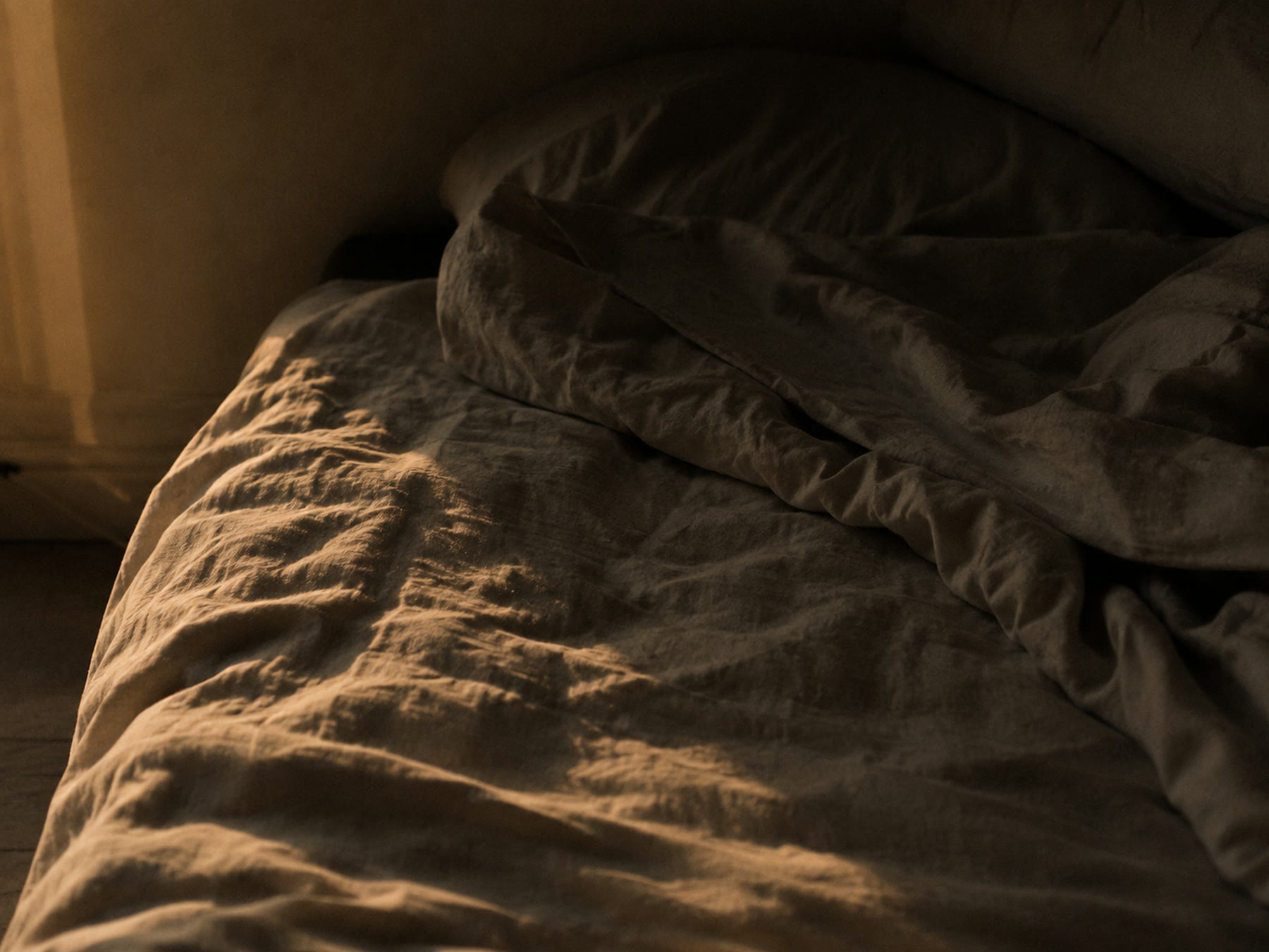 Rumpled linen bedding lit by low evening light