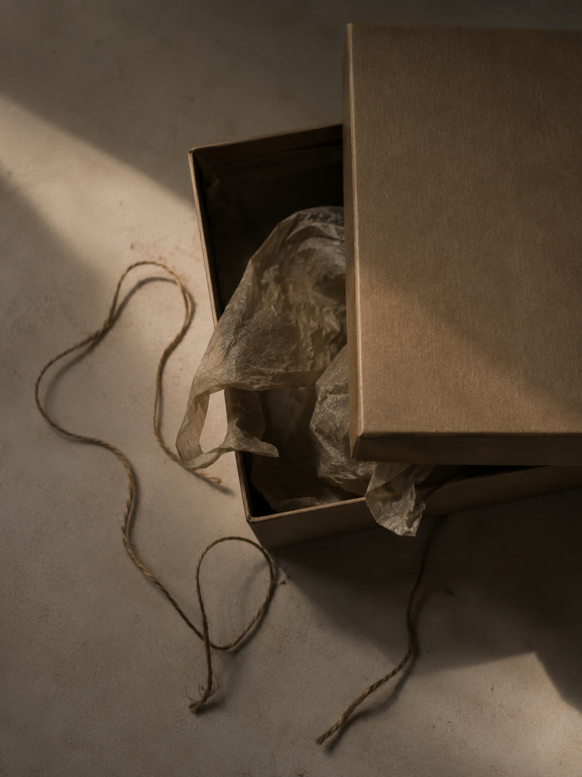 An unbleached kraft gift box with tissue and twine